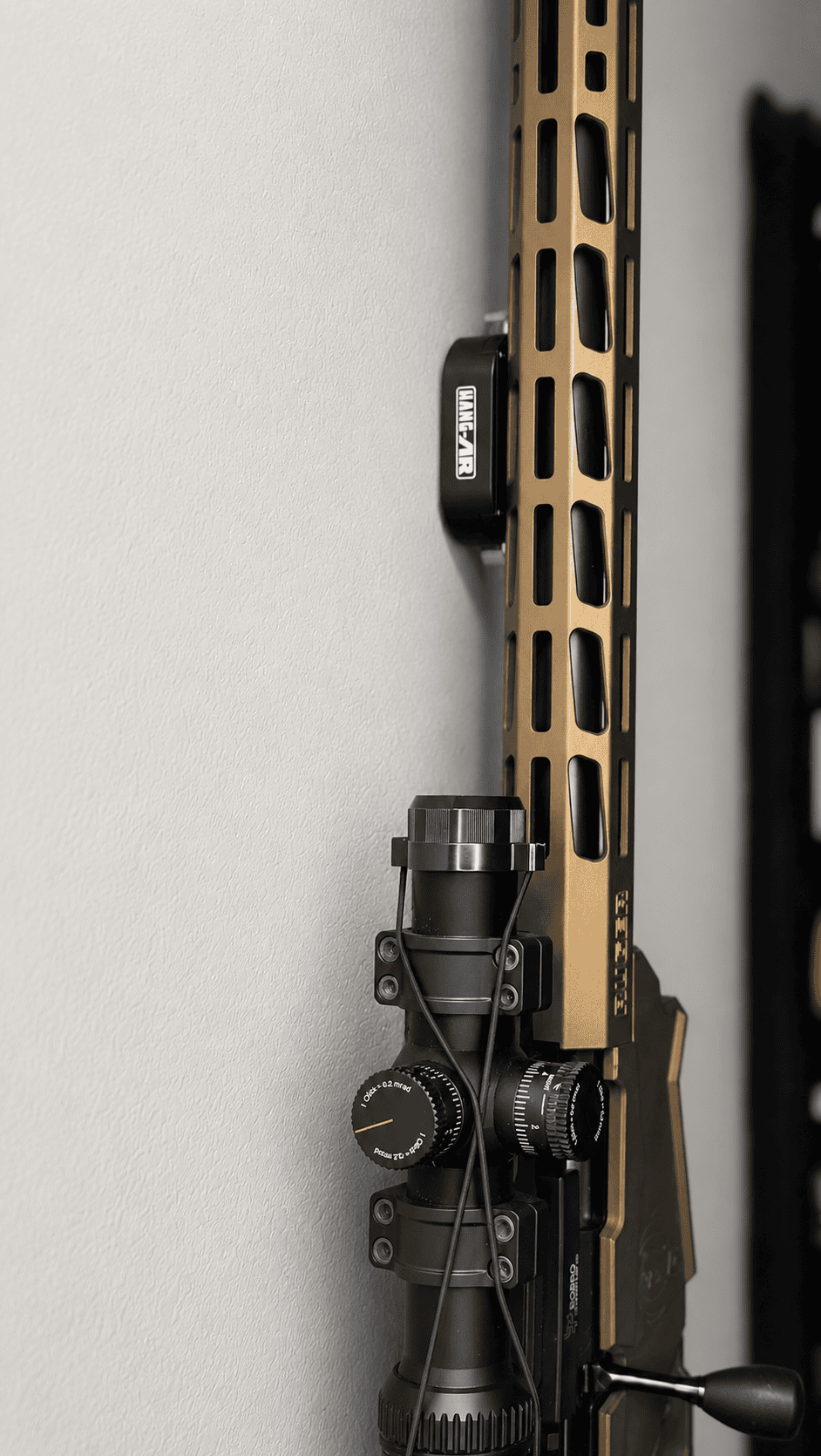 Tan rifle displayed vertically on a wall using a Hang-AR Quick-Detach STEALTH M-LOK mount